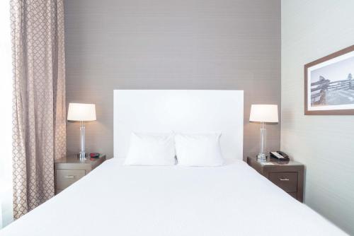 a bedroom with a large white bed with two lamps at Sandman Hotel Abbotsford Airport in Abbotsford