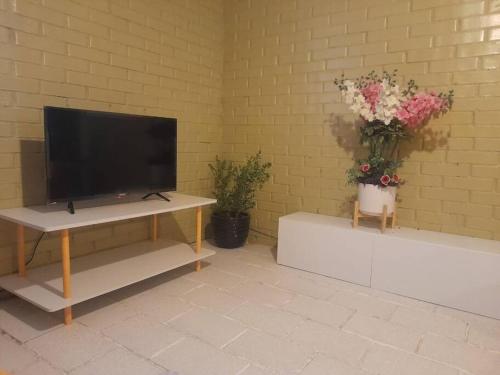 a living room with a flat screen tv and flowers at Hospedaje Mamá Rosita in Tlaxcala de Xicohténcatl