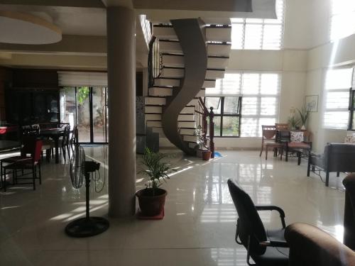 a lobby with a spiral staircase and tables and chairs at JD Homestays CDO in Cagayan de Oro