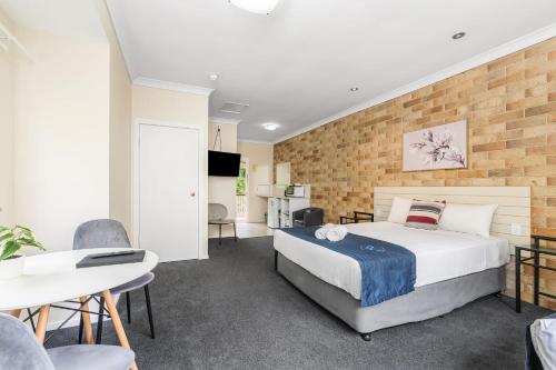 a bedroom with a bed and a brick wall at Lismore Wilson Motel in Lismore