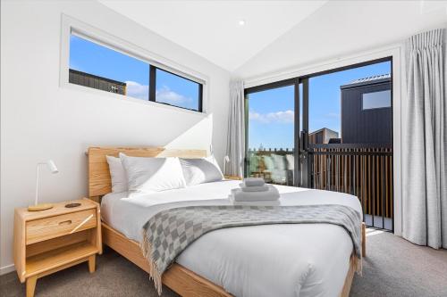 a bedroom with a bed and a large window at Modern 2BR Townhouse in Mission Bay I Zodiak Stays in Auckland