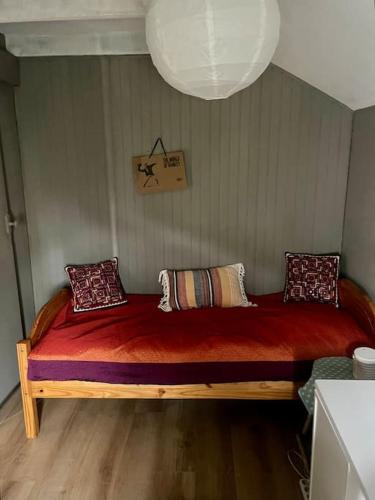 - une chambre dotée d'un lit en bois avec des draps et des oreillers rouges dans l'établissement Maison proche Paris Stade de France, à Aubervilliers
