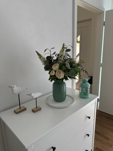 a vase with flowers on top of a dresser at Apartmán Květinová zahrada in Prague
