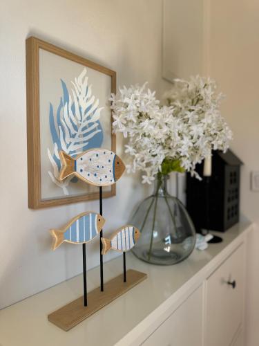 three wooden fish on a shelf next to a vase at Apartmán Květinová zahrada in Prague