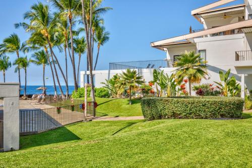 a house with palm trees in front of the ocean at Royal Sea Cliff Kona by OUTRIGGER - Select Your Unit in Kailua-Kona