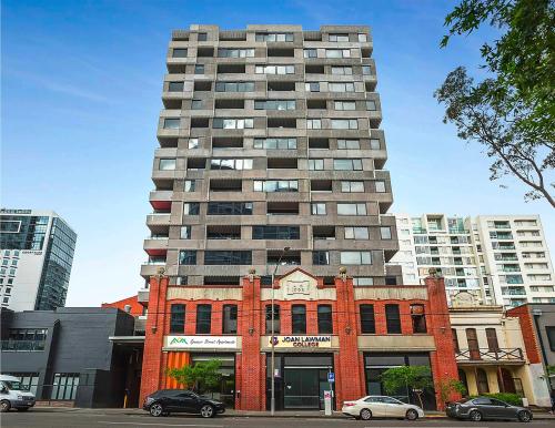 a tall building in front of a red brick building at Spencer Street Apartments in Melbourne