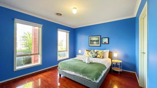 a blue bedroom with a bed and two windows at Blue Home by GoodLive in Morang