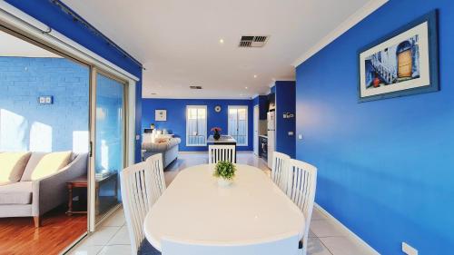 a dining room with blue walls and a white table and chairs at Blue Home by GoodLive in Morang
