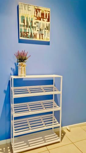 a white shelf in a room with a painting on the wall at Blue Home by GoodLive in Morang