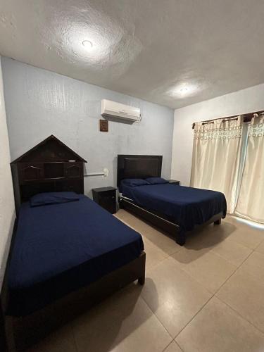 two beds in a room with blue sheets at Casa Kanté in Tamasopo