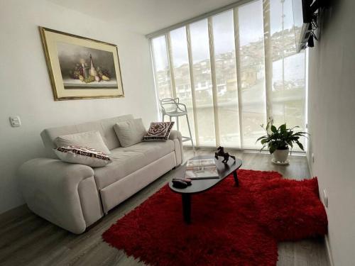 a living room with a couch and a red rug at Apartamento frente a Mallplaza in Manizales