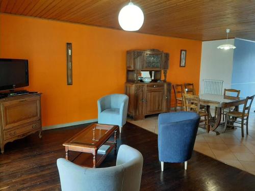 - un salon avec des murs orange, une table et des chaises dans l'établissement Charentaise rénovée avec jardin, à 20 min d'Angoulême - FR-1-653-90, à Champagne-de-Blanzac