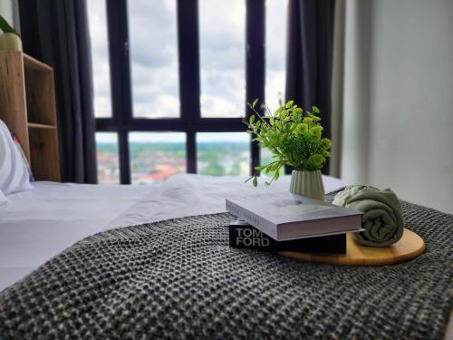 a table with a book and a vase with a plant at Studio E Sofo Apartment Suria Jaya -Shah Alam in Shah Alam