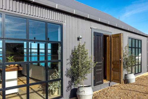 a building with large windows and a door at Loft & Workroom, Woodside Bay - Be My Guest Waiheke in Rocky Bay