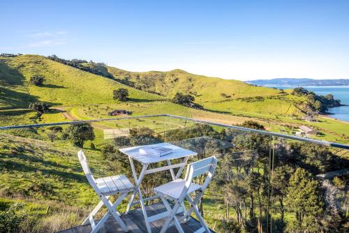 a table and two chairs sitting on top of a hill at Loft & Workroom, Woodside Bay - Be My Guest Waiheke in Rocky Bay