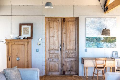 a room with a wooden door and a table at Loft & Workroom, Woodside Bay - Be My Guest Waiheke in Rocky Bay