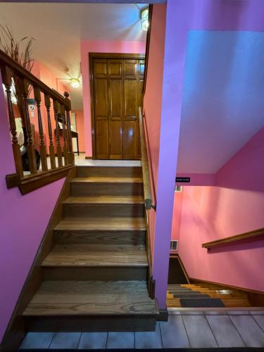 a staircase with a wooden door and pink walls at Full House/Heart of Worcester in Worcester