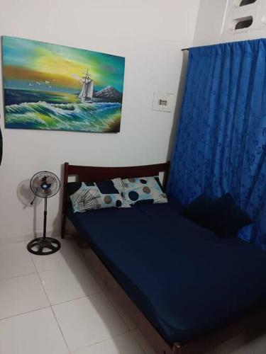 a bedroom with a blue bed with a painting on the wall at Acogedor apartamento familiar in Mariquita