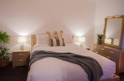 a bedroom with a bed with two lamps and a mirror at Evergreen On Baillie in Horsham