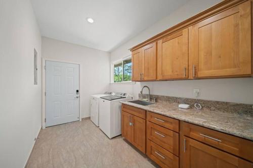 a kitchen with wooden cabinets and a sink and a dishwasher at HAWAII PARADISE 3Bd2a Home w Pool and FirePit near Ocean in Keaau