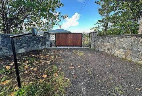 a garage with a wooden gate and a stone fence at HAWAII PARADISE 3Bd2a Home w Pool and FirePit near Ocean in Keaau