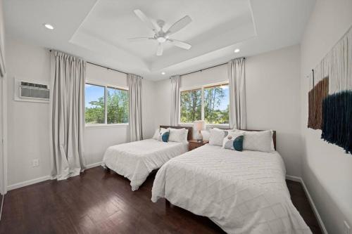 a white bedroom with two beds and a ceiling fan at HAWAII PARADISE 3Bd2a Home w Pool and FirePit near Ocean in Keaau
