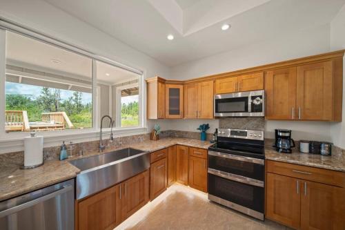 a kitchen with wooden cabinets and a large window at HAWAII PARADISE 3Bd2a Home w Pool and FirePit near Ocean in Keaau