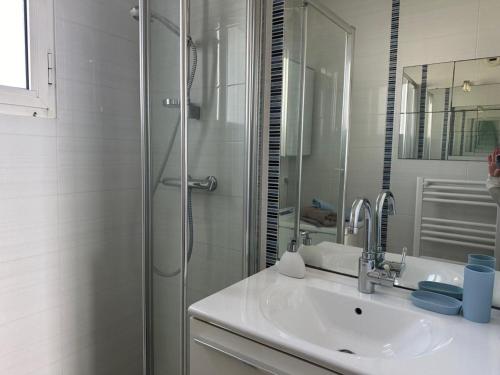 ein weißes Badezimmer mit Waschbecken und Dusche in der Unterkunft Notre-Dame-de-Monts (85) - Appartement de vacances 45m² environ - 4 personnes - FR-1-540-294 in Notre-Dame-de-Monts