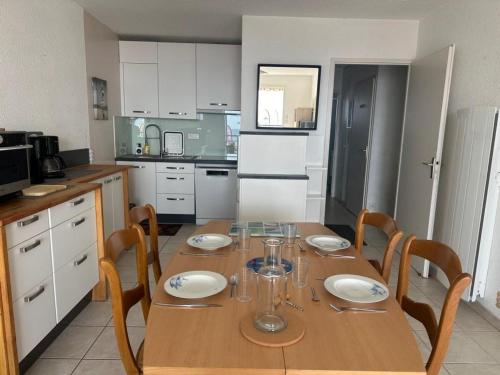une cuisine avec une table en bois et des chaises ainsi qu'une salle à manger dans l'établissement Appartement rénové 4 pers - Face mer - PARKING - Animaux admis - FR-1-540-294, à Notre-Dame-de-Monts