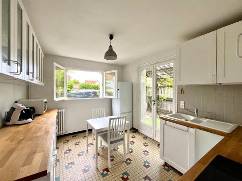 une cuisine avec des armoires blanches et une table et des chaises dans l'établissement Maison calme avec cour et terrasse proche Aiguillon - Parking - FR-1-319-578, à Arcachon