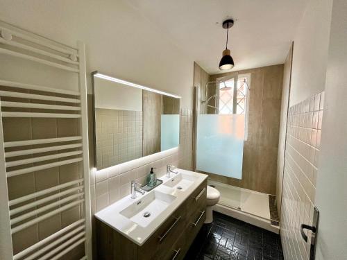 une salle de bain avec un lavabo et un miroir et des toilettes dans l'établissement Maison calme avec cour et terrasse proche Aiguillon - Parking - FR-1-319-578, à Arcachon