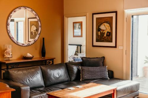 a living room with a leather couch and a mirror at Port Boutique Accommodation in Port Fairy