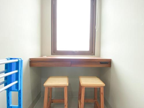 two wooden stools under a window in a room at Comfort 1BR at Gateway Park LRT City Jatibening Apartment By Travelio in Bekasi