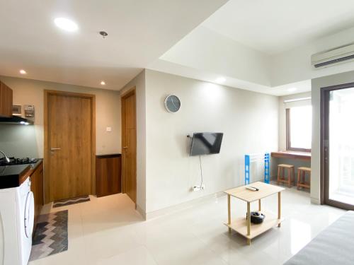 a living room with a tv and a table at Comfort 1BR at Gateway Park LRT City Jatibening Apartment By Travelio in Bekasi