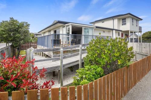 a white house with a wooden porch and a fence at Modern 2-Bedroom Oasis Just Steps from the Beach in Christchurch