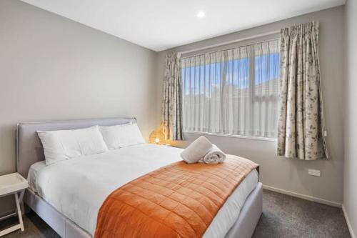 een slaapkamer met een bed en een groot raam bij Modern 2-Bedroom Oasis Just Steps from the Beach in Christchurch