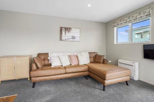 a living room with a couch and a tv at Modern 2-Bedroom Oasis Just Steps from the Beach in Christchurch