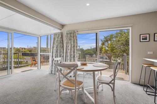 a dining room with a table and chairs and a balcony at Modern 2-Bedroom Oasis Just Steps from the Beach in Christchurch