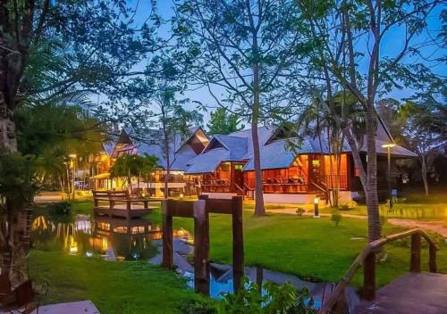 a house with a pond in front of it at อภิรตา รีสอร์ท in Nan