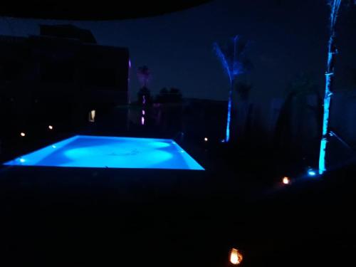 a swimming pool at night with blue lights at Ferme Hind , magnifique ferme avec grande piscine et un jardin splendide in Marrakech