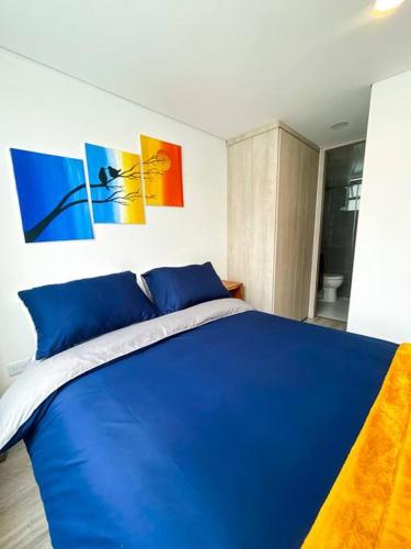 a blue bed in a bedroom with paintings on the wall at Apartamento Colibrí in Tunja
