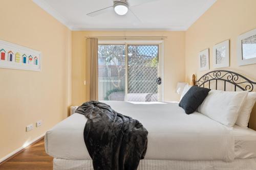 a bedroom with a large white bed with a window at Shelly Golf & Beach Retreat in Shelly Beach