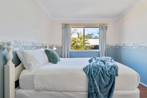 a bedroom with a white bed and a window at Shelly Golf & Beach Retreat in Shelly Beach