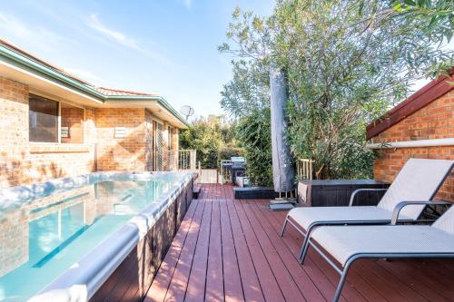 a deck with a swimming pool and two lounge chairs at Shelly Golf & Beach Retreat in Shelly Beach