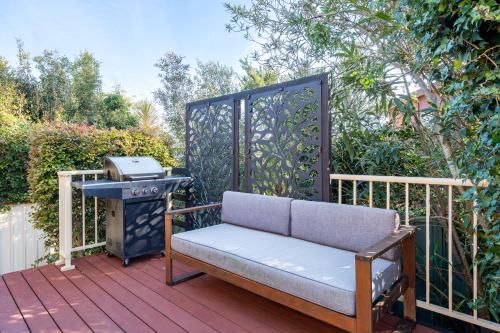 a bench sitting on a deck with a grill at Shelly Golf & Beach Retreat in Shelly Beach