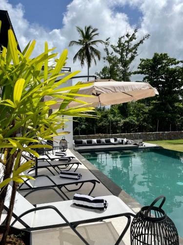 a pool with chairs and umbrellas next to a resort at Casa B&W - Luxury Frente a Mar A 3 Minutos de la playa in Las Galeras