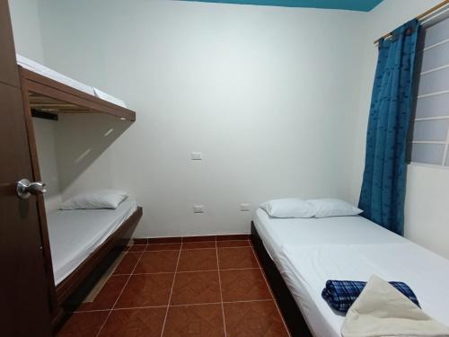 two beds in a small room with blue curtains at Ding-Dong Hostel in Cali