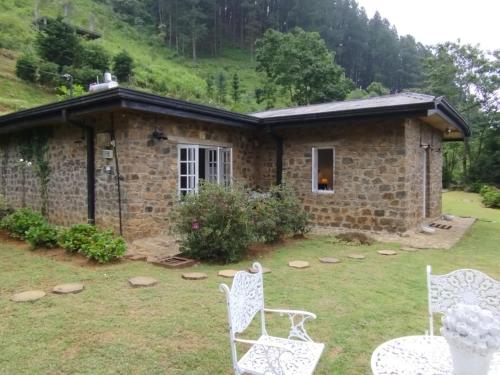 a stone house with two white chairs in the yard at 4154ft in ramboda in Ramboda