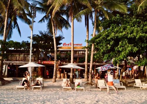 a group of people sitting on the beach under umbrellas at Red Coconut Beach Hotel Boracay in Boracay