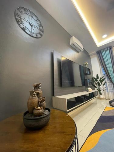 a living room with a clock on the wall and a table at D’Lora Homestay in Malacca